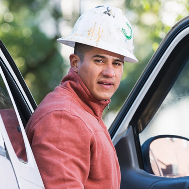 Man in white hard hat stepping out of car