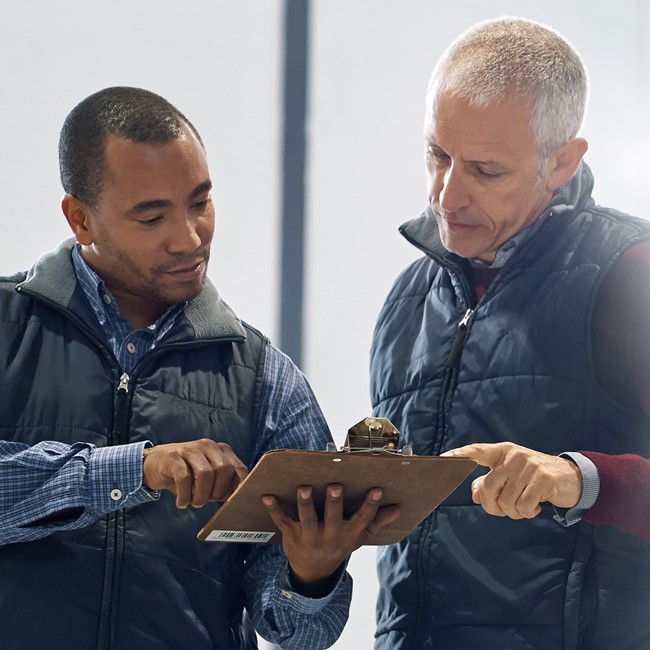 Two men looking at clipboard
